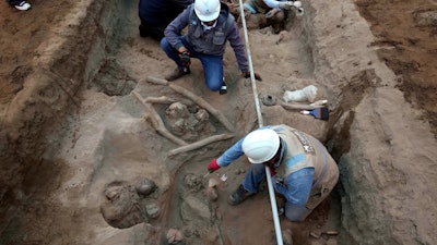 Archaeologists uncover bones and vessels discovered by city workers who were digging a natural gas line for the company Calidda in the district of Carabayllo on the outskirts of Lima, Peru, Friday, Sept. 22, 2023.