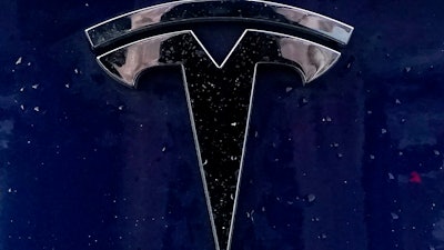 A Tesla electric vehicle emblem is affixed to a passenger vehicle, Feb. 21, 2021, in Boston.