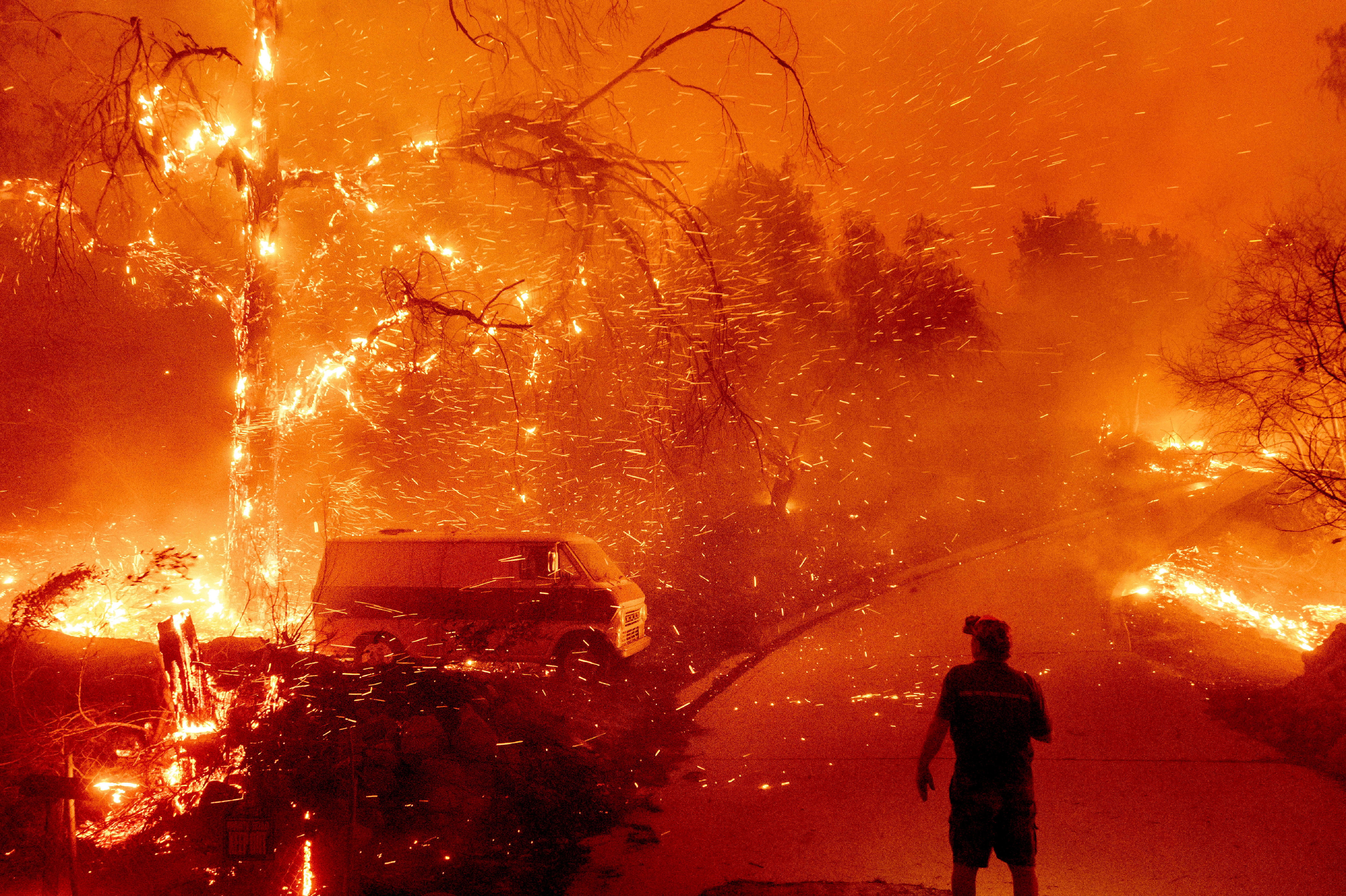 Bruce McDougal watches embers fly over his property as the Bond Fire burns through the Silverado community in Orange County, Calif., Dec. 3, 2020.