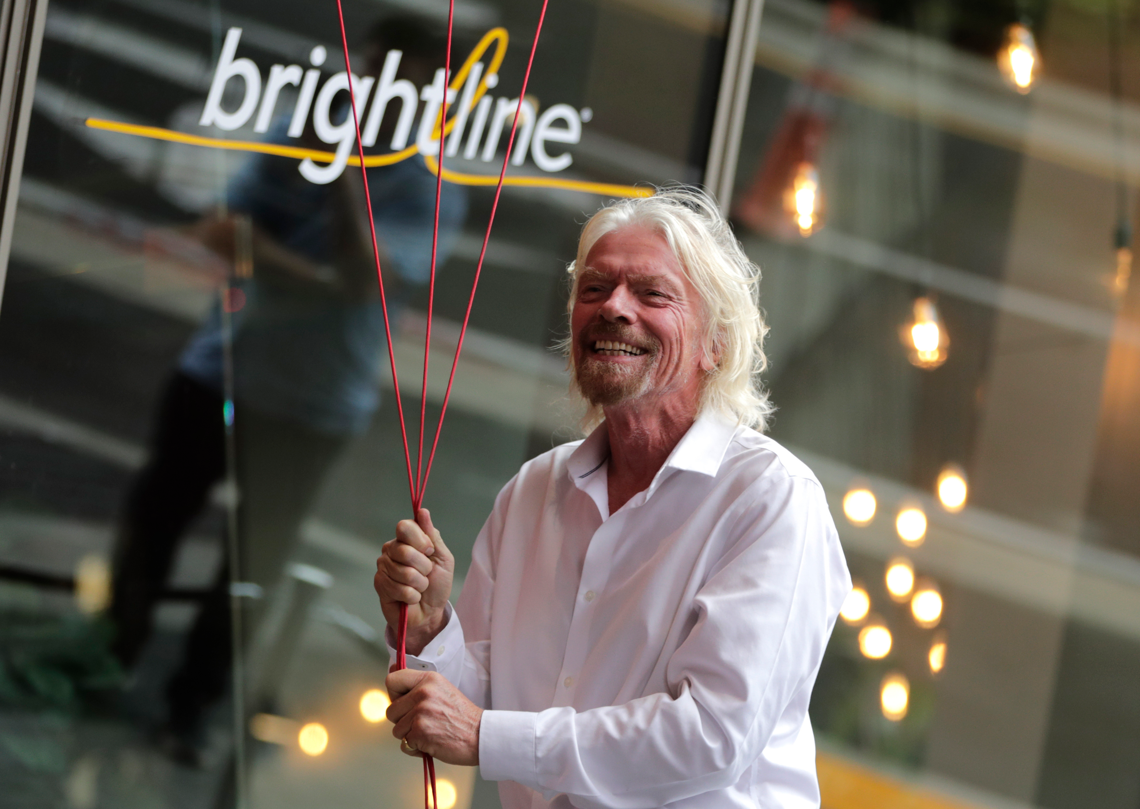 Richard Branson, of Virgin Group, prepares to unfurl a banner during a naming ceremony for the Brightline train station, to be renamed as Virgin MiamiCentral in Miami on April 4, 2019.