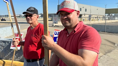 Striking United Auto Workers member Chris Jedrzejek, right, and his father picket outside Ford Motor Co.'s Michigan Assembly Plant Monday, Oct. 2, 2023, in Wayne, Mich.
