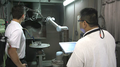 Nick Armenta (left), regional manager with Olympus Controls, and Juan Puente, thermal spray supervisor at Dallas manufacturer Aircraft Tooling, discuss the spray process now handled by a collaborative robot from Universal Robots.
