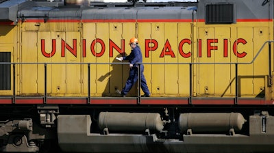 A maintenance worker walks past the company logo on the side of a locomotive in the Union Pacific Railroad fueling yard in north Denver, Oct. 18, 2006. Union Pacific announced Wednesday, Nov. 1, 2023, that it is trimming the ranks of the railroad's management employees as part of the new CEO's push to eliminate layers of bosses involved in decisions.