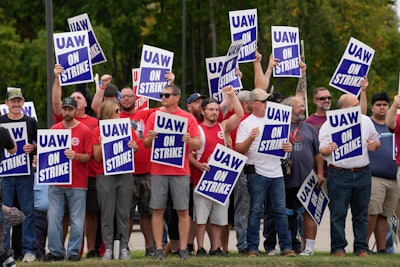 United Auto Workers members hold picket signs near a General Motors assembly plant in Delta Township, Mich., Sept. 29, 2023.