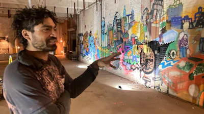 Alex Smith of Minneapolis, who goes by the tag 'Shock' in his painting, describes a graffiti history of the former Pillsbury Mills plant, Nov. 9, 2023, in Springfield, Ill. Walls of mill buildings were given to Shock and other artists for 'Visitors Art Exhibits' in November.