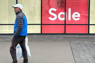 A shopper passes by a sign trumpeting a sale at a clothing store in the Thornton Premium Outlets Monday, Dec. 18, 2023, in Thornton, Colo. On Wednesday, the Conference Board reports on U.S. consumer confidence for December.