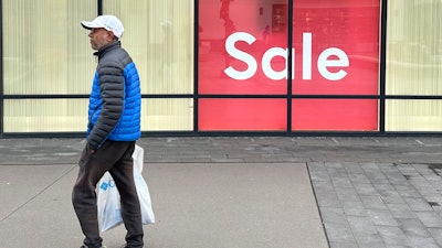 A shopper passes by a sign trumpeting a sale at a clothing store in the Thornton Premium Outlets Monday, Dec. 18, 2023, in Thornton, Colo. On Wednesday, the Conference Board reports on U.S. consumer confidence for December.