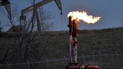 A flare burns at a well pad Aug. 26, 2021, near Watford City, N.D.