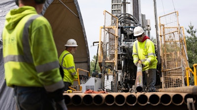 Driller Helper Chris Palmer, right, attaches a core sampling tube to a drilling rig at the Talon Metals Corporation drilling site, June 7, 2023, near Tamarack, Minn.