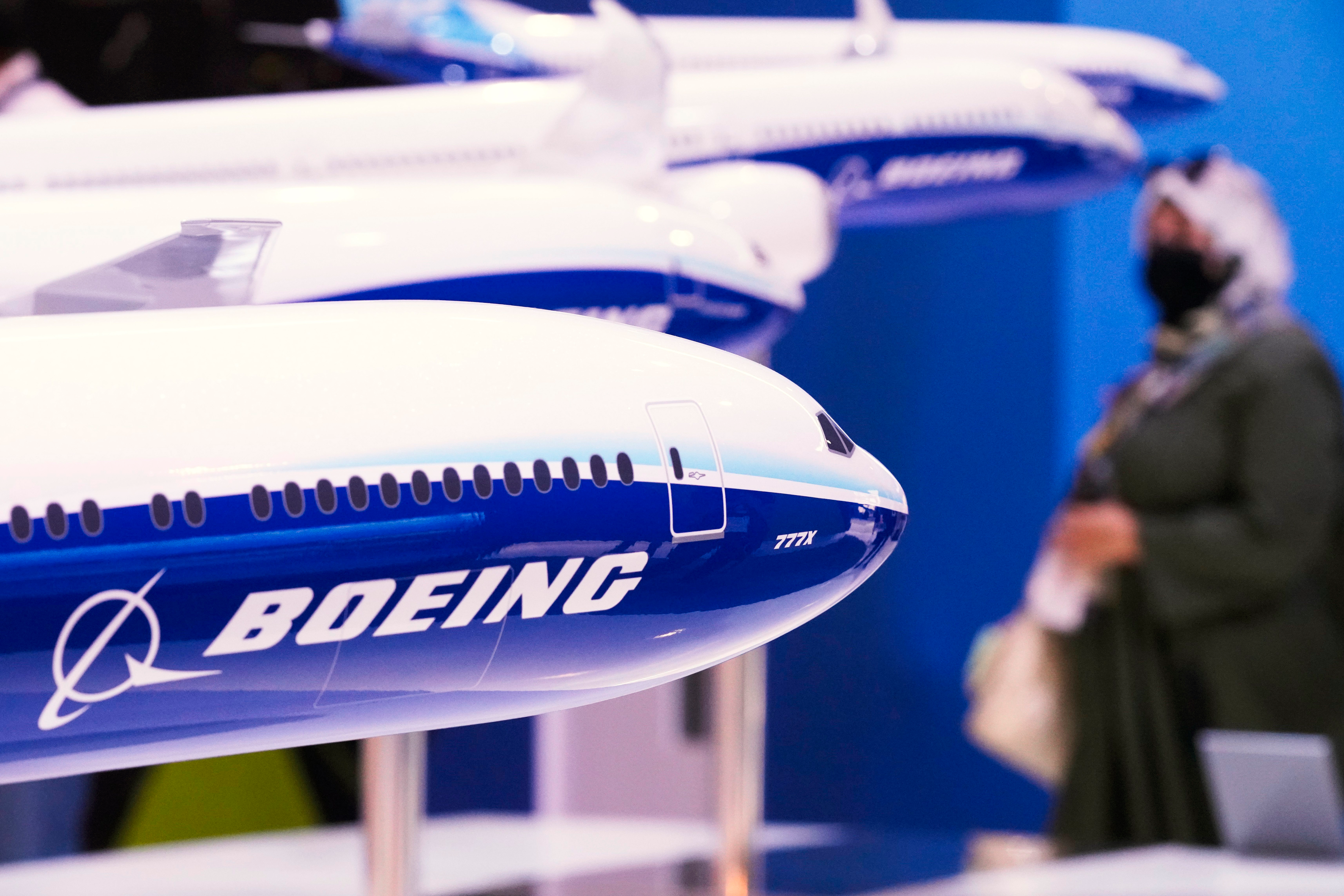 A woman walks by models of Boeing Co. aircraft, including the manufacturer's new Boeing 777X, at the Dubai Air Show in Dubai, United Arab Emirates, Wednesday, Nov. 17, 2021.