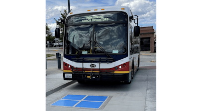 Municipal bus approaching a wireless inductive charging pad.
