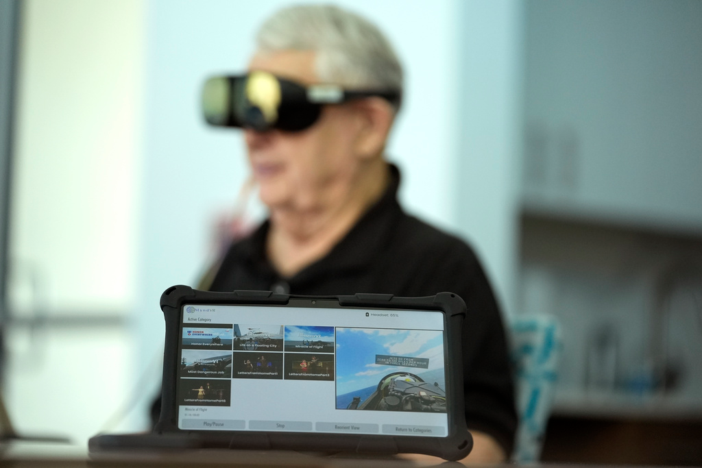 A screen displays a visual of being in a Navy fighter jet as retired Army Col. Farrell Patrick, 91, wears a Mynd Immersive virtual reality headset at John Knox Village, Wednesday, Jan. 31, 2024, in Pompano Beach, Fla.