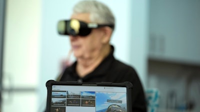 A screen displays a visual of being in a Navy fighter jet as retired Army Col. Farrell Patrick, 91, wears a Mynd Immersive virtual reality headset at John Knox Village, Wednesday, Jan. 31, 2024, in Pompano Beach, Fla.