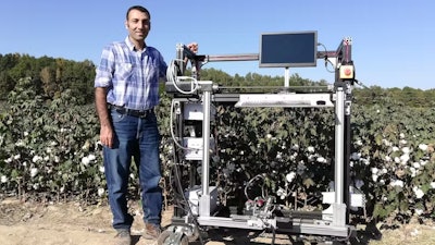 Mississippi State University engineering professor Hussein Gharakhani with a prototype robotic cotton harvester.