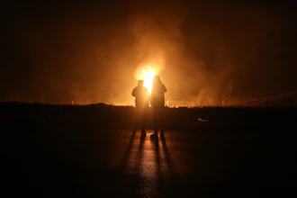 Two men look at flames after a natural gas pipeline explodes outside the city of Boroujen in the western Chaharmahal and Bakhtiari province, Iran, in early Wednesday, Feb. 14, 2024.