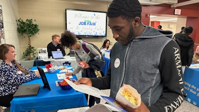 Job seeker Johannes Oveida looks over a brochure at a job fair at Lehigh Carbon Community College, Allentown, Pa., March 7, 2024.