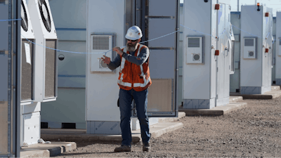 Workers do checks on battery storage pods at Orsted's Eleven Mile Solar Center lithium-ion battery storage energy facility Thursday, Feb. 29, 2024, in Coolidge, Ariz.