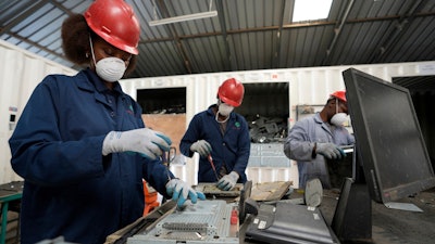 Employees dismantle laptop waste at WEEE center recycling plant, a collection point where people can deposit old electric equipment in Nairobi, Kenya Wednesday, March. 20, 2024.