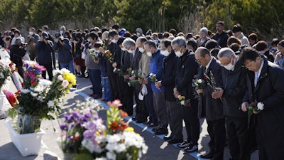 People observe a moment of silence at 2:46 p.m., the moment the earthquake struck in Iwaki, Fukushima prefecture, northern Japan Monday, March 11, 2024.
