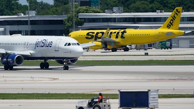 A JetBlue Airways Airbus A320, left, passes a Spirit Airlines Airbus A320 as it taxis on the runway, July 7, 2022, at the Fort Lauderdale-Hollywood International Airport in Fort Lauderdale, Fla.