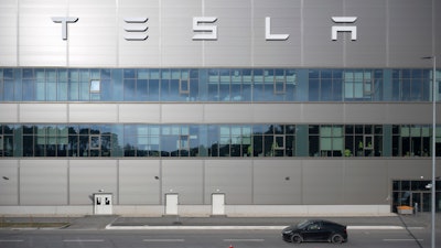 A vehicle from the security service drives by the Tesla car factory after production came to a standstill and workers were evacuated following a power outage, in Grünheide, Germany, Tuesday, March 5, 2024.