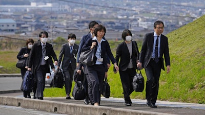 Japan's health ministry officials walk towards a plant operated by a subsidiary of Kobayashi Pharmaceutical Co. to conduct an on-site inspection in Kinokawa, south of Osaka, western Japan, Sunday, March 31, 2024. Japanese government health officials on Sunday inspected a factory producing health supplements linked to several deaths and the hospitalization of more than 100 others, one day after the authorities investigated another plant that manufactured the product.