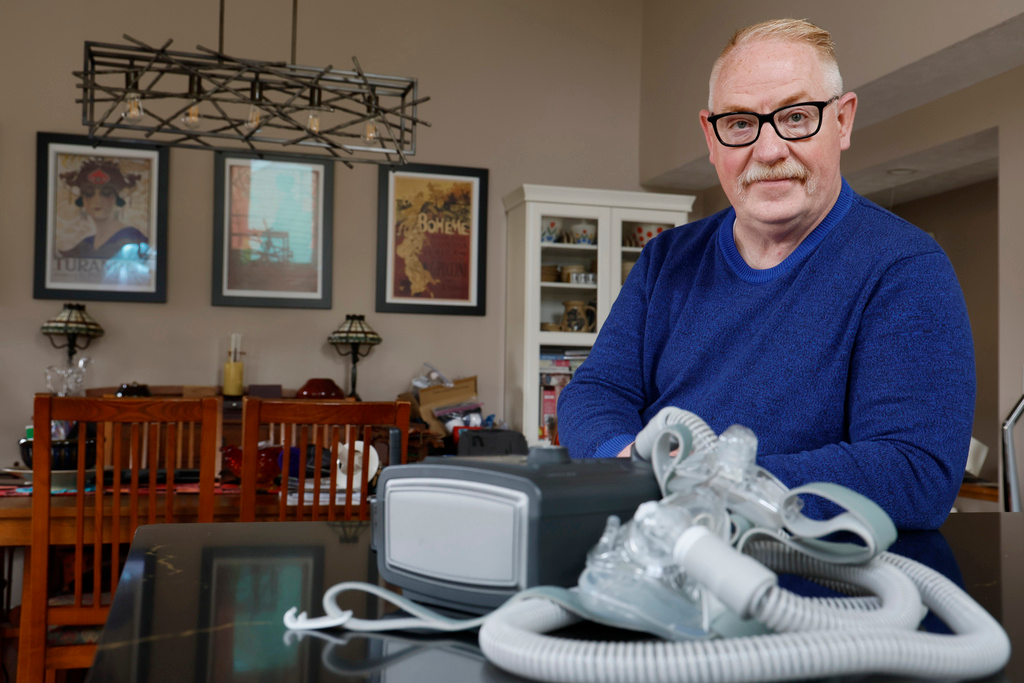 Jeffrey Reed, who experienced persistent sinus infections and two bouts of pneumonia while using a Philips CPAP machine, poses with the device at his home, Oct. 20, 2022, in Marysville, Ohio.