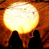 People watch the sunset at a park on an unseasonably warm day, Feb. 25, 2024, in Kansas City, Mo.