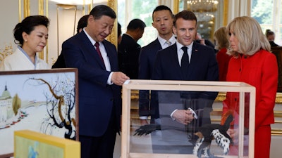 China's President Xi Jinping, second left, presents gifts to French President Emmanuel Macron at the Elysee Palace, Paris, May 6, 2024.
