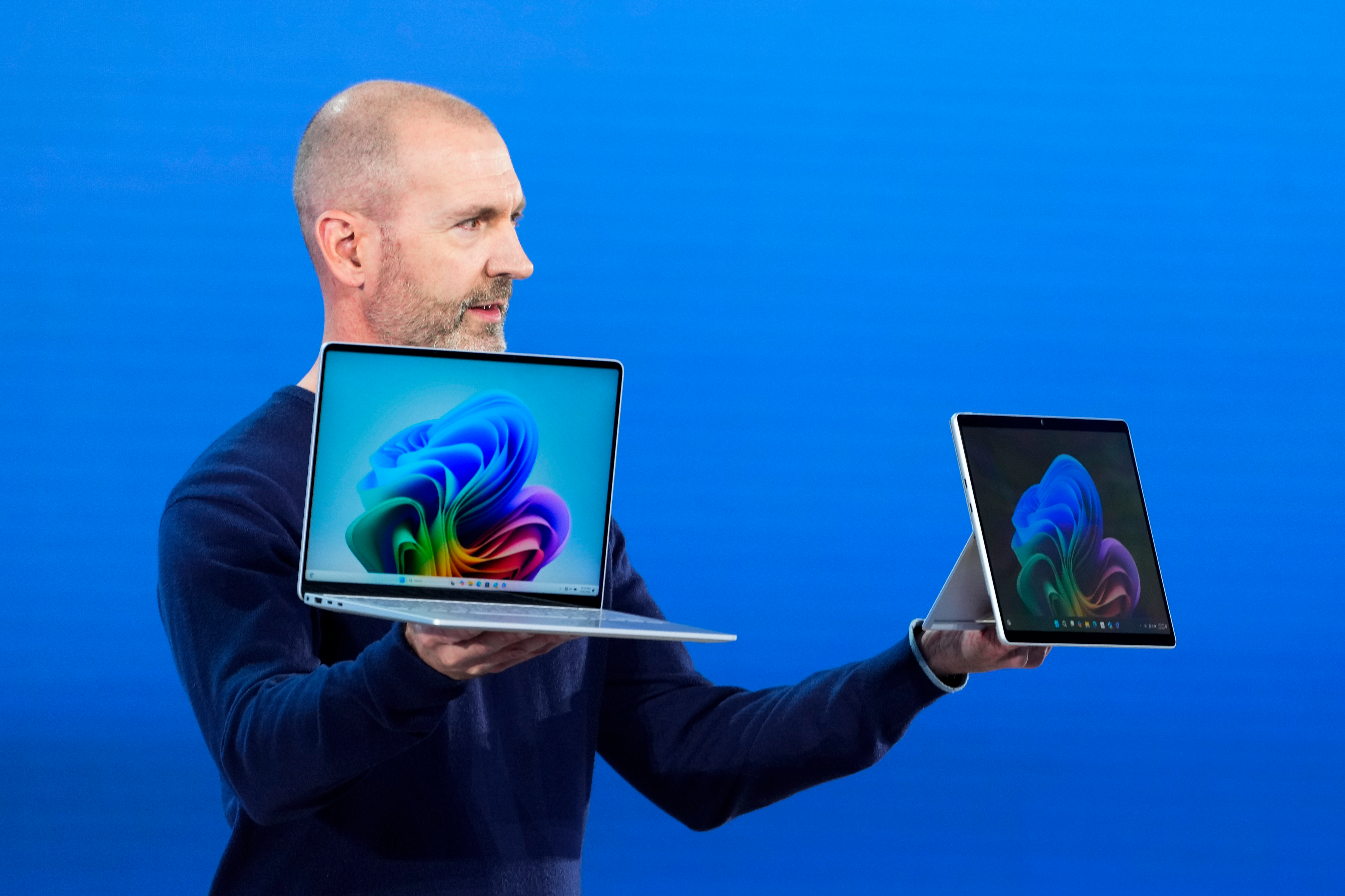 Brett Ostrum, Microsoft corporate vice president of Surface, holds up the new Surface Laptop and Surface Pro with built-in AI hardware during a showcase event of the company's AI assistant, Copilot, at Microsoft headquarters, Monday, May 20, 2024, in Redmond, Wash.
