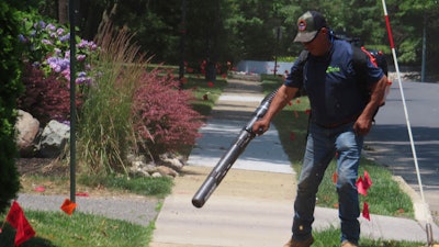 Antonio Espinoza, a supervisor with the Gras Lawn landscaping company, uses a gasoline-powered leaf blower to clean up around a housing development in Brick, N.J. on June 18, 2024.
