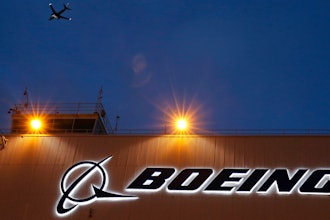 An airplane flies over a sign on Boeing's newly expanded 737 delivery center, Oct. 19, 2015, at Boeing Field in Seattle.