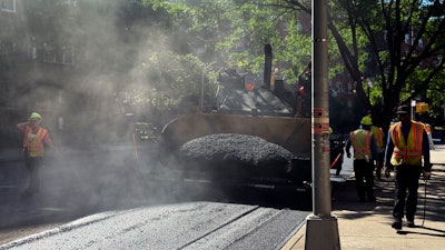 A road crew repaves a road in the Forest Hills neighborhood in the Queens borough of New York.