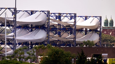 Giant wind turbine blades for the Vineyard Winds project are stacked on racks in the harbor, July 11, 2023, in New Bedford, Mass.