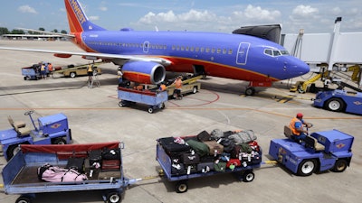 Baggage carts are towed to the Boeing 737 jet at Bill and Hillary Clinton National Airport in Little Rock, Ark.