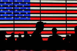 People gather near an electronic display of an American flag in Times Square in New York on Aug. 9, 2024.