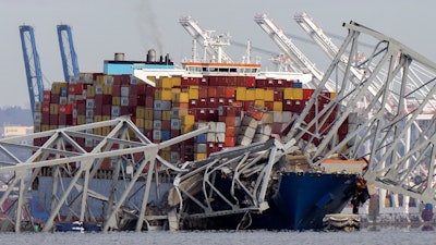 The cargo ship Dali is stuck under part of the structure of the Francis Scott Key Bridge after the ship hit the bridge, Tuesday, March 26, 2024, as seen from Pasadena, Md.