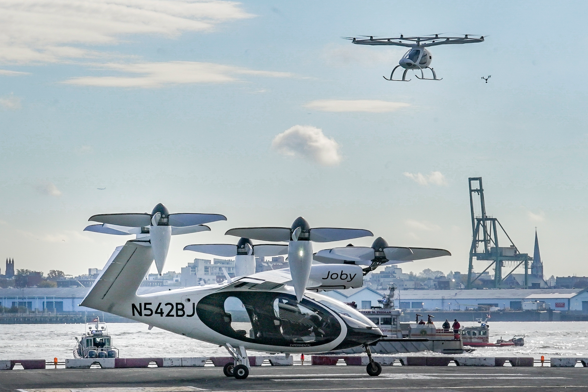 An electric vertical takeoff and landing (eVTOL) aircraft, flies above the Joby eVTOL aircraft, during a demonstration of eVTOLs Nov. 13, 2023, in New York.
