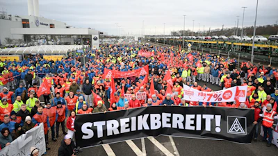 Volkswagen workers march holding a sign with writing reading in German 'Ready to Strike!' on the first day of a nationwide warning Volkswagen workers' strike, in Zwickau, Germany, Monday, Dec. 2, 2024.