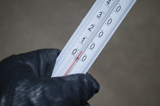 A gloved hand holding a mercury thermometer.