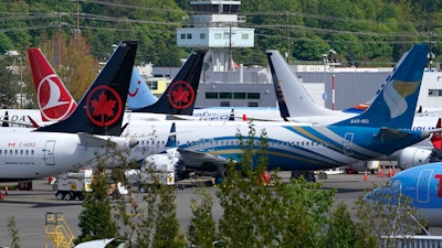 Boeing 737 Max airplanes, belonging to Air Canada and other airlines, sit parked in a storage lot, Monday, April 26, 2021, near Boeing Field in Seattle.