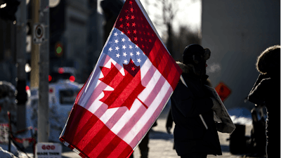 A protester holds the flags of Canada and the United States outside on Parliament Hill in Ottawa, on Saturday, Feb. 1, 2025.