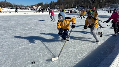 Hockey players go for the puck during the final of the women's open division at the pond hockey classic in Meredith, N.H., on Sunday, Feb. 4, 2024.