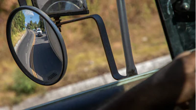 Trucks loaded with avocados are seen reflected on a rear view mirror as they are escorted by the police on their way to the city of Uruapan, in Santa Ana Zirosto, Michoacan state, Mexico, Jan. 26, 2023.