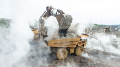 A backhoe loads material into a mining dump truck at a nickel mining operation in South Sulawesi, Indonesia.