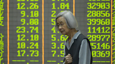 An investor stands in front of stock price indices at a brokerage house, Hangzhou, China, April 7, 2025.