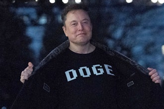 Elon Musk flashes his T-shirt that reads 'DOGE' to the media as he walks on South Lawn of the White House, in Washington, March 9, 2025.