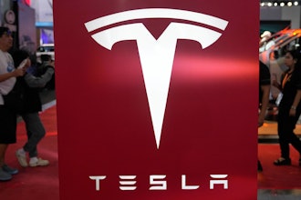 People pass by a Tesla sign at the Manila International Auto Show in Pasay city, Philippines Friday, April 11, 2025.