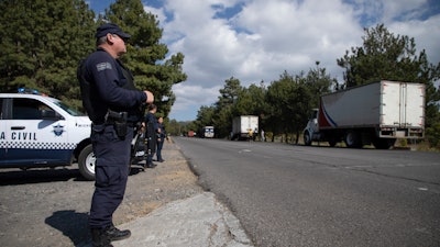 Police guard trucks loaded with avocados on their way to the city of Uruapan in Santa Ana Zirosto, Michoacan state, Mexico, Jan. 26, 2023.
