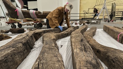 Research assistant Alyssa Carpenter inspects timbers from of a wooden Revolutionary War-era gunboat to prepare for the craft's partial reconstruction at the New York State Museum, Friday, May 30, 2025, in Albany, New York.